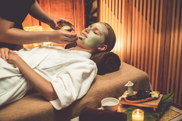 Serene ambiance of spa salon, woman customer indulges in rejuvenating with luxurious face cream massage with warm lighting candle. Facial skin treatment and beauty care concept. Quiescent