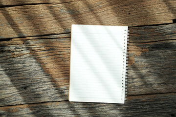 White notebook with ring binder on old rustic wood table under sunlight