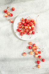 yellow cherries on a white platter, scattered on the table, natural light, top view,