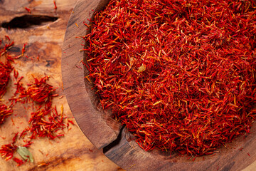 Spice saffron threads, in a wooden bowl, on a wooden table, top view, close-up,