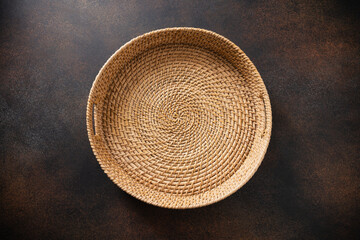 Round Woven wicker basket, tray or plate on dark rustic surface. Handmade by local craftsmen in sri...