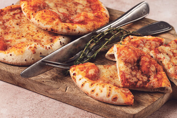 Four pizzetta Margaritas, on a cutting board, on a light gray surface, top view,