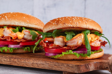 Shrimp burgers with fresh ingredients are served on a wooden board in a bright kitchen,