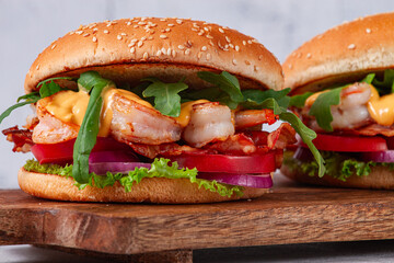 Shrimp burgers with fresh ingredients are served on a wooden board in a bright kitchen,