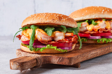 Shrimp burgers with fresh ingredients are served on a wooden board in a bright kitchen,