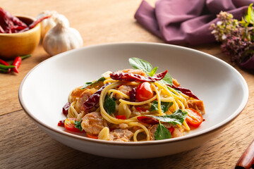 Stir fried Spaghetti with Thai-Isan fermented pork and rice sausage (Northeastern Sausage).pasta with chilli garlic and Northeastern Thai Sausage in white plate.Thai fusion food.