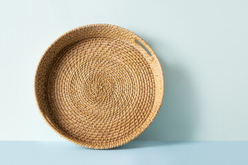 Round woven wicker basket, tray or plate stand on blue background. Handmade by local craftsmen in...