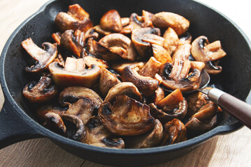fried mushrooms champignons. on a cast-iron frying pan, natural light, close-up,