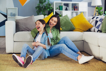 Mother and daughter bonding at home on a joyful weekend, enjoying quality time together in a cozy...