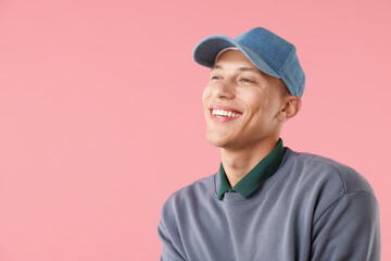 Young man in stylish baseball hat on pink background, space for text