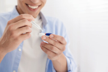 Man taking contact lens out of case at home, closeup. Space for text