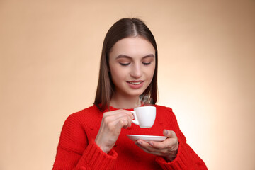 Smiling woman with cup of coffee on beige gradient background