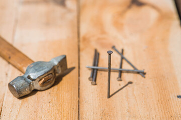 Close-up of a hammer and nails on wooden boards. Hand tools, old construction tools.