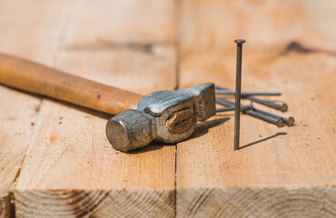 Close-up of a hammer and nails on wooden boards. Hand tools, old construction tools.
