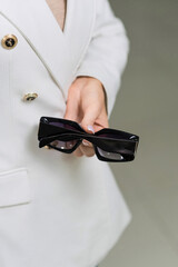 Close-up of the hands of an elegant young brunette woman who holds sunglasses in an optical store. Choosing eyeglasses to buy, vision, protection, lifestyle, fashion