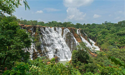 This majestic waterfall in between the dense green forest and clear blue sky can simply take the...