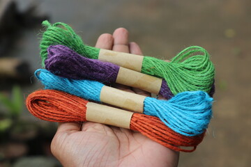 Holding a group of multicolored jute thread twine. Colored jute rope for hobby and crafts