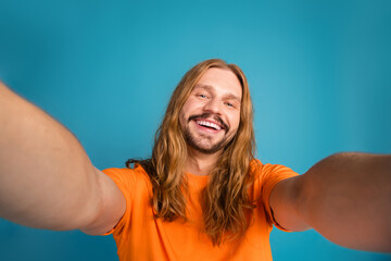 Smiling young man in orange t-shirt posing enthusiastically for a photo, showing a casual and...