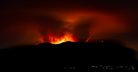 Flames and red glow from a forest fire with mountain in the foreground. The image is from the Holy...