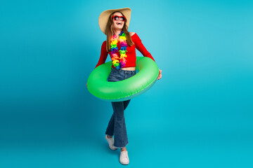 Young stylish woman in a summer look with a green inflatable ring on a blue background, radiating...