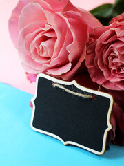 Wooden price tag and pink roses. Flower shop.