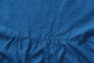 A close-up of a textured blue fabric with subtle wrinkles, showcasing its softness and fluidity