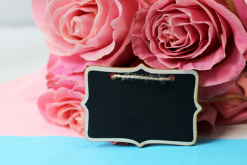 Wooden price tag and pink roses. Flower shop.