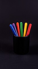 Black-colored pencils in a black pencil holder on a dark background