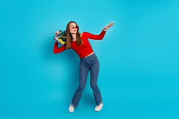 Trendy young woman in casual style with a retro boombox against a blue background showcasing...