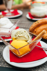 Italian coffee break in cafe during holiday season with pistachio and mango scoops of gelato with freshly baked croissants