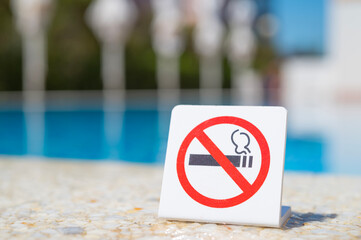 Attention, do not smoke. No smoking sign. Smoking is prohibited in public places. Prohibitory sign near blue water in the pool. 