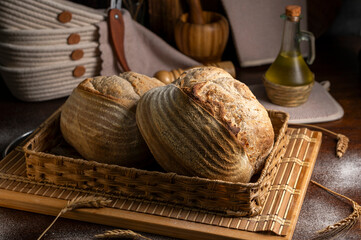 Healthy, organic, whole and sliced ​​homemade sourdough bread with ham and cheese on a wooden table and kitchen utensils with an airy crumb and crispy crust. 
