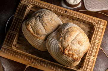 Healthy, organic, whole and sliced ​​homemade sourdough bread with ham and cheese on a wooden table and kitchen utensils with an airy crumb and crispy crust. 