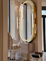 Modern beauty salon interior with golden oval mirror and styling chair