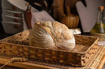 Healthy, organic, whole and sliced ​​homemade sourdough bread with ham and cheese on a wooden table and kitchen utensils with an airy crumb and crispy crust. 