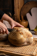 Healthy, organic, whole and sliced ​​homemade sourdough bread with ham and cheese on a wooden table and kitchen utensils with an airy crumb and crispy crust. 