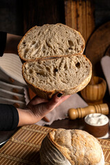 Healthy, organic, whole and sliced ​​homemade sourdough bread with ham and cheese on a wooden table and kitchen utensils with an airy crumb and crispy crust. 