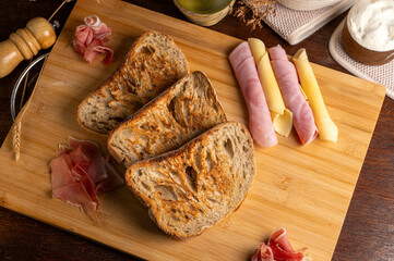 Healthy, organic, whole and sliced ​​homemade sourdough bread with ham and cheese on a wooden...
