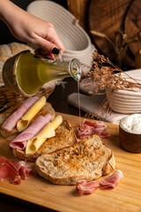 Healthy, organic, whole and sliced ​​homemade sourdough bread with ham and cheese on a wooden table and kitchen utensils with an airy crumb and crispy crust. 