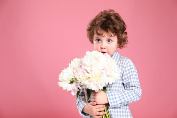 Cute little boy with bouquet of beautiful peonies on pink background. Space for text