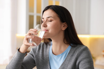 Woman drinking water from glass in kitchen