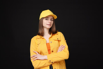 Young woman wearing stylish yellow baseball hat on black background