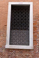 Close-up of traditional Venetian window with wrought iron grille and stone frame