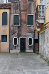 Aged and colorful facade of a residential building in a peaceful courtyard in Venice, showing textured walls and timeless atmosphere.
