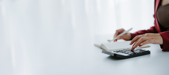 Business woman hand using calculator to calculate the financial results. work from home concept