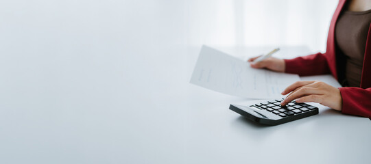 Business woman hand using calculator to calculate the financial results. work from home concept