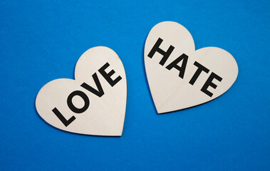 Love vs Hate symbol. Concept word Love vs Hate on wooden hearts. Beautiful blue background....
