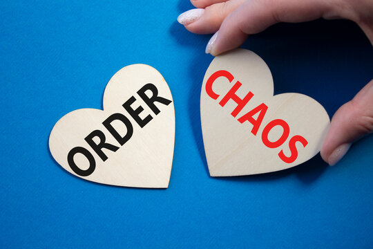 Chaos or Order symbol. Concept word Chaos or Order on wooden hearts. Businessman hand. Beautiful blue background. Business and Chaos or Order concept. Copy space