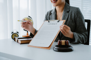 Lawyers discuss a contract on a clipboard, with one pointing to specific terms with a pen, while a...