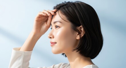 Fototapeta premium A beautiful asian woman with radiant skin gazes thoughtfully, her natural beauty enhanced by subtle makeup and a fresh, clean look